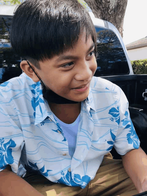 a young boy wearing a blue and white shirt and a black mask