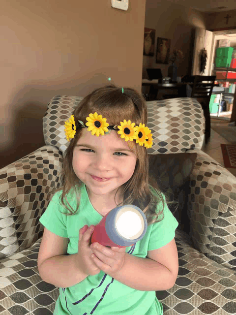 a little girl with a flower crown on her head holds a flashlight