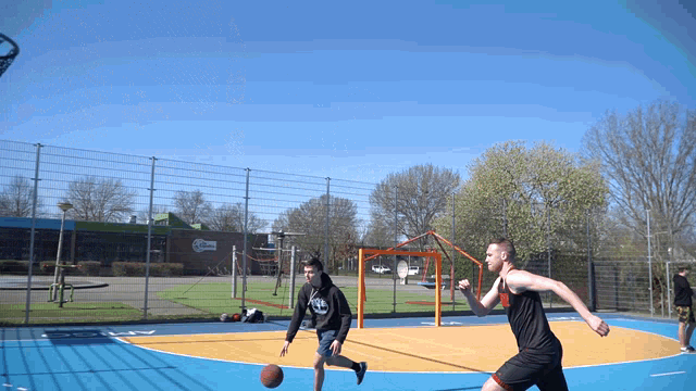 two men are playing basketball on a court with one wearing a black hoodie that says ' aa ' on it