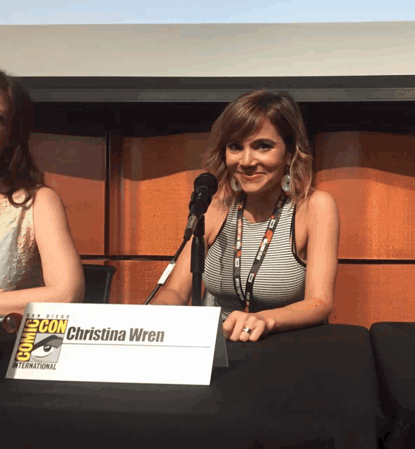 a woman sitting at a table with a name plate that says christina wren