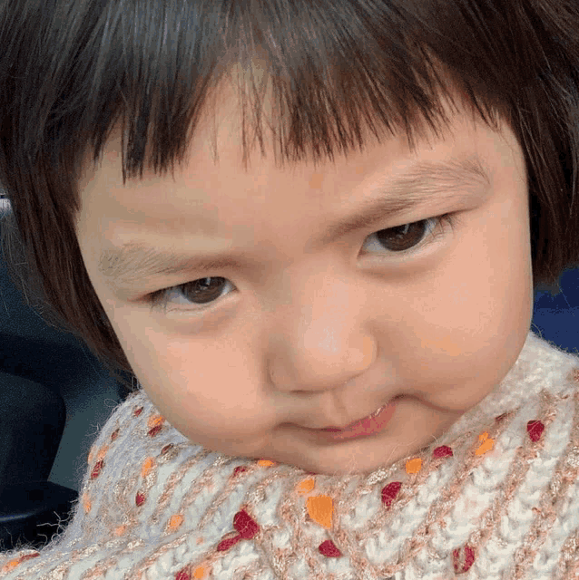 a close up of a child 's face with a white sweater on