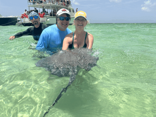 a man wearing a shirt that says ' fishing ' on it is holding a stingray in the water