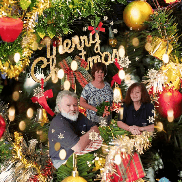 a merry christmas sign hangs from the ceiling above a group of people