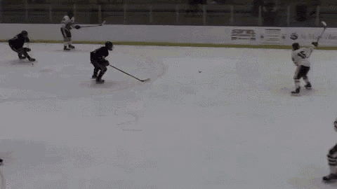 a group of hockey players are playing a game on the ice . one of the players has the number 12 on his jersey .