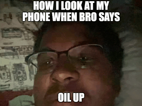 a man wearing glasses is laying in bed with the caption how i look at my phone when bro says oil up ..