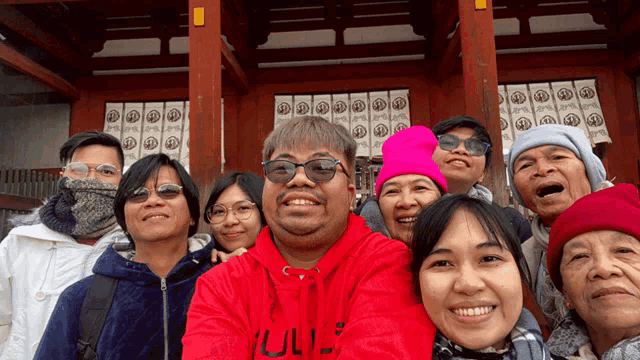 a group of people posing for a picture with a man wearing a red sweatshirt that says ' ul ' on it