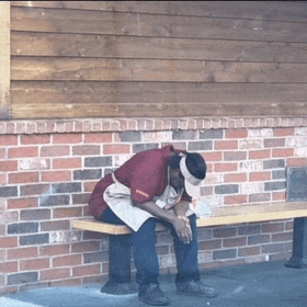 a man sits on a bench in front of a brick wall that says ' a ' on it