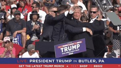 a man in a suit is holding a trump sign in front of a crowd