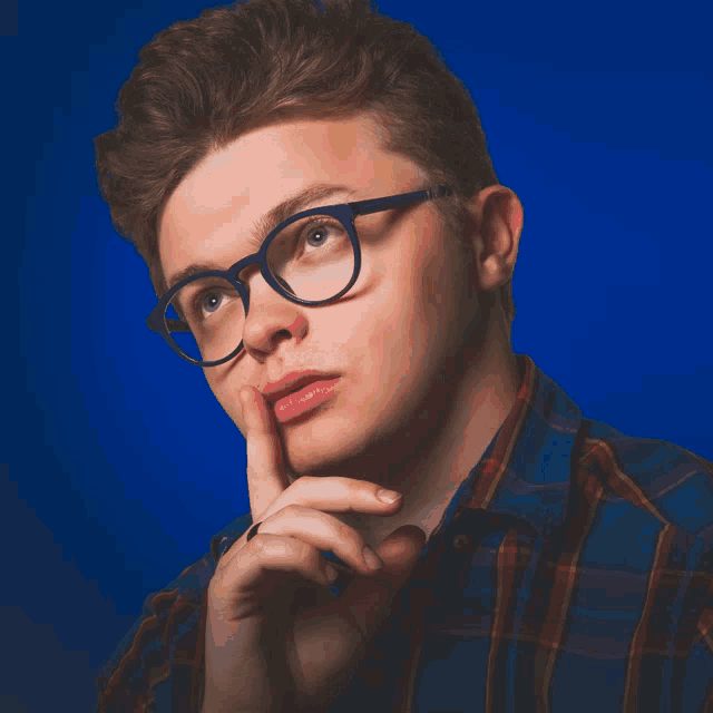 a man wearing glasses and a plaid shirt is thinking