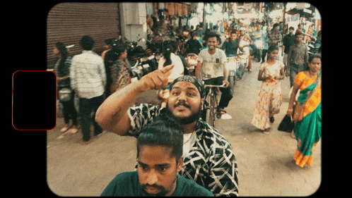 a man with a beard is pointing at something in a crowd of people