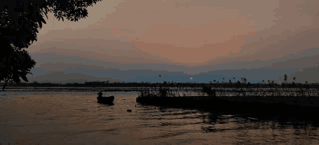 a man in a small boat is fishing in the water at sunset