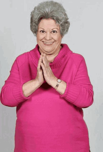 an older woman wearing a pink sweater and a watch