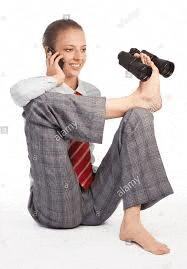 a woman in a suit and tie is sitting on the floor talking on a cell phone and holding binoculars .