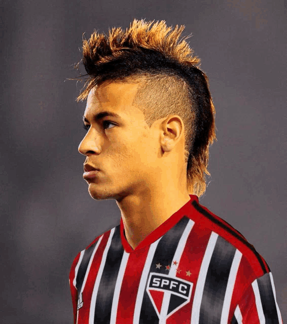 a man with a mohawk is wearing a red and black striped shirt that says spfc