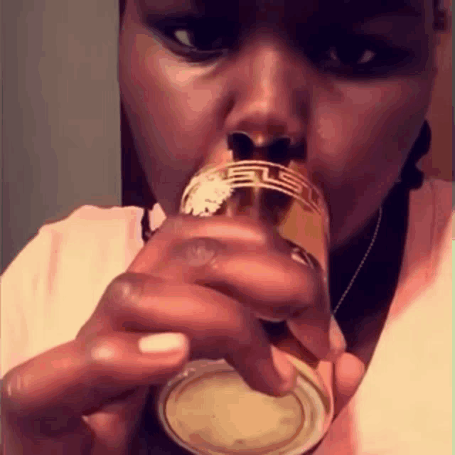 a woman is drinking from a glass with the letter ls on it