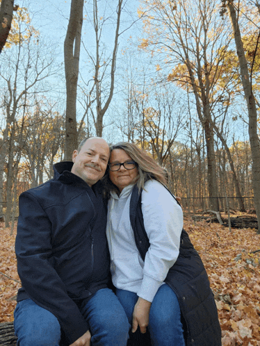 a man and a woman are posing for a photo in the woods