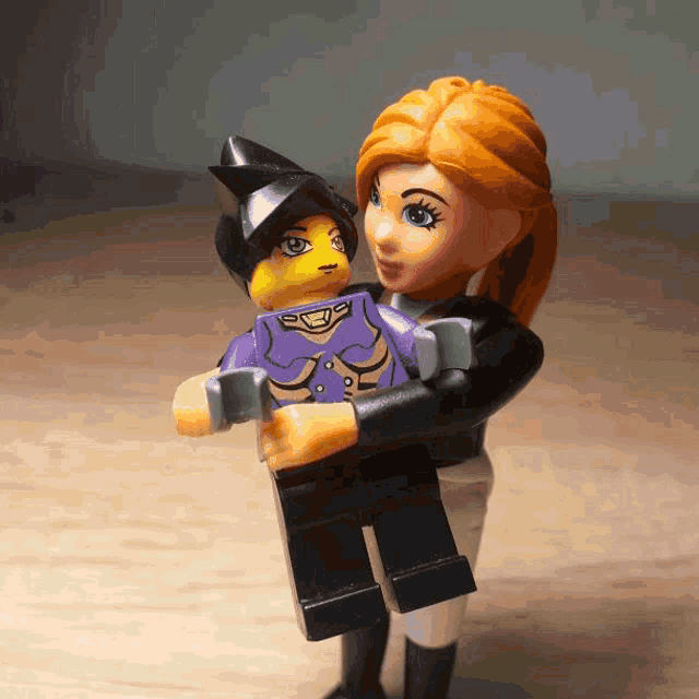 a woman is holding a lego figure with a purple shirt on