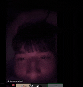 a person 's face is visible in a dark room with a few icons on the bottom of the screen