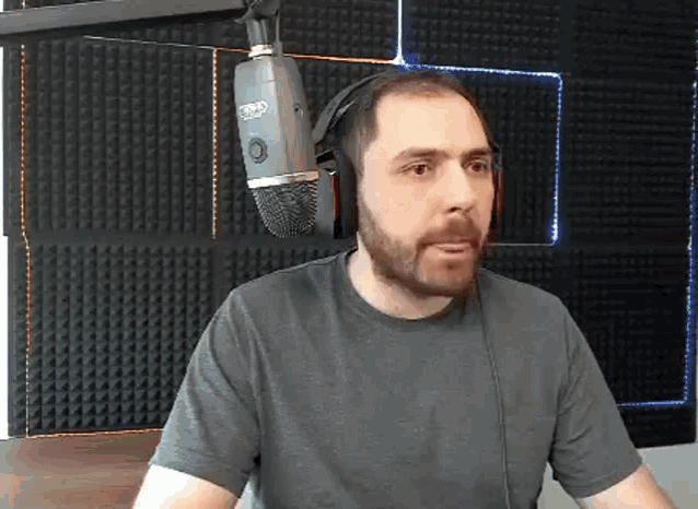 a man with a beard is wearing headphones and a microphone in a studio .