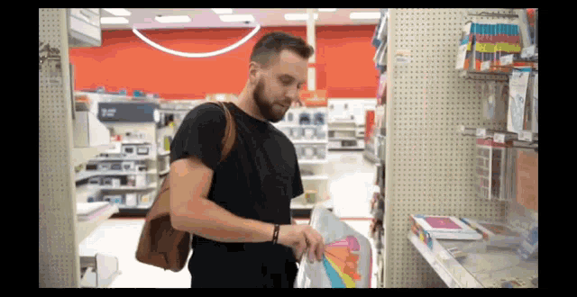 a man in a black shirt is standing in a store looking at a piece of paper with a rainbow on it