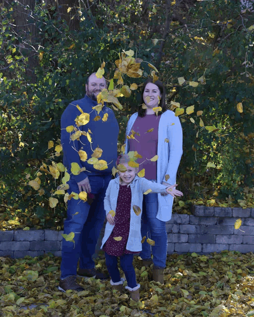 a family is posing for a picture with leaves flying around them