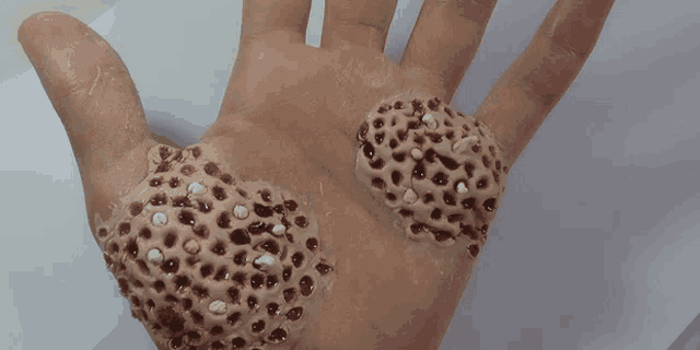 a close up of a person 's hand with holes in it and blood coming out of it