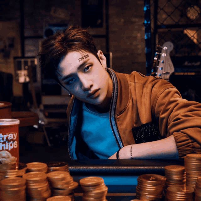 a man with a tattoo on his face is sitting at a table with stacks of gold coins