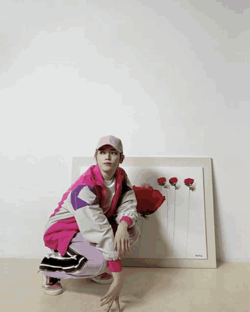 a woman squatting in front of a framed picture of flowers