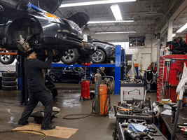 a man in a black shirt is working on a car