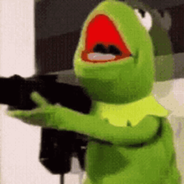 kermit the frog from the muppet show is holding a gun in his hand .