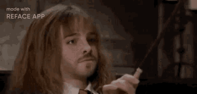 a man with long hair and a beard is holding a wand and making a face .