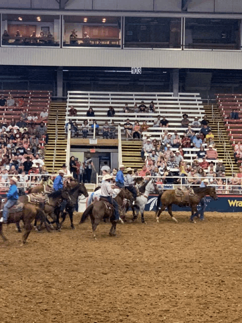 people riding horses in a rodeo arena with a sign that says wrangler on it