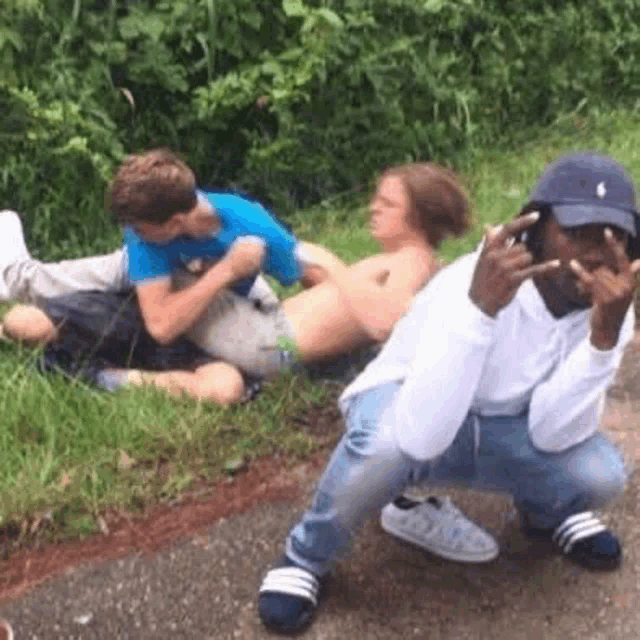 a group of young men are sitting on the grass and one of them is squatting down .