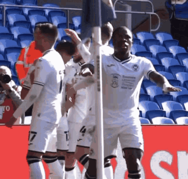 a group of soccer players are celebrating a goal in front of a sign that says ' sr ' on it