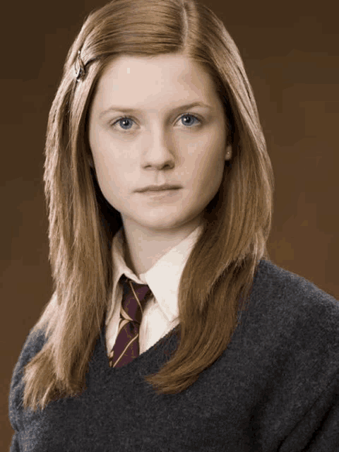 a girl with long red hair is wearing a grey sweater and tie