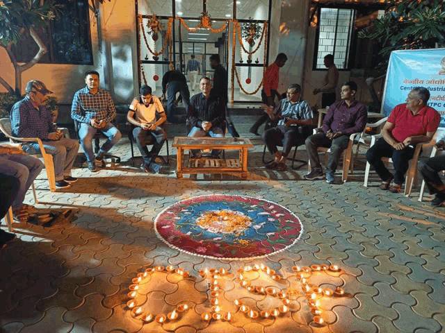 a group of people are sitting around a table with candles in the shape of the letter o on the ground