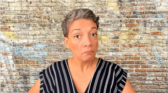 a woman wearing a striped shirt is making a funny face in front of a brick wall