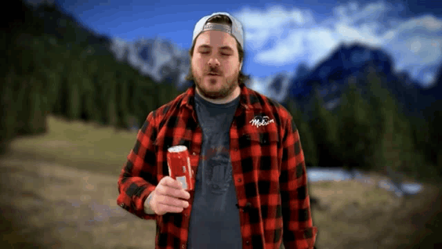 a man in a plaid shirt is holding a can of coke