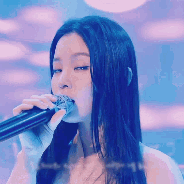 a woman is singing into a microphone with a blue background