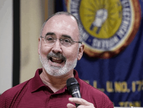 a man holding a microphone in front of a banner that says electrical