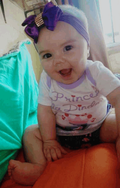 a baby wearing a purple headband and a shirt that says princess on it