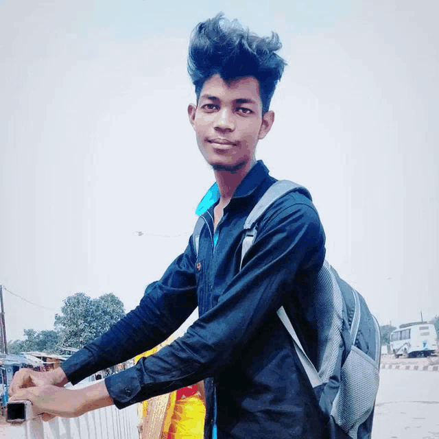 a young man wearing a black shirt and a backpack poses for a photo