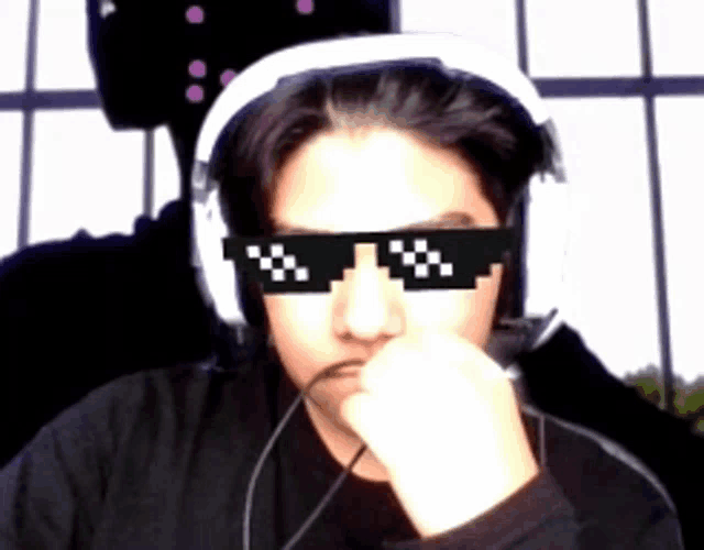 a man wearing headphones and sunglasses has his hand on his face