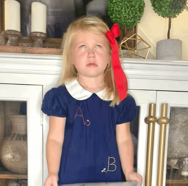 a little girl wearing a blue dress with the letter a and b on it