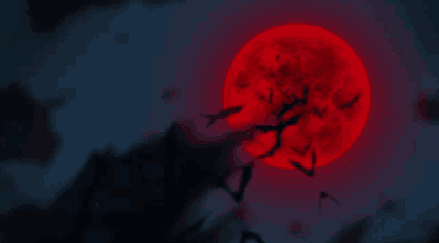 a full red moon is behind a tree with bats flying around it