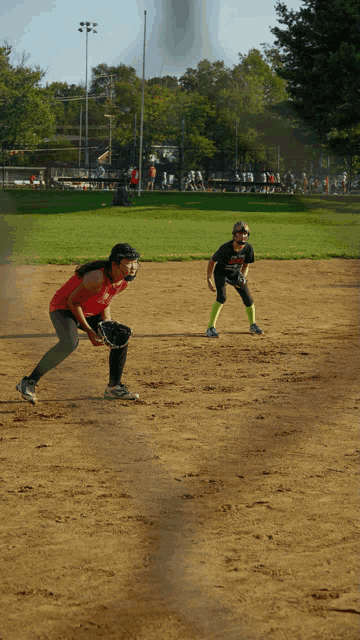 a girl in a red shirt is playing softball with a man in a black shirt with the word eagles on it