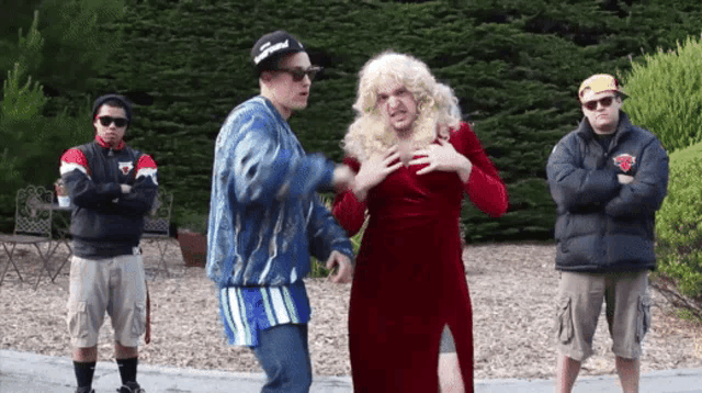 a man wearing a hat that says supreme stands next to a woman in a red dress