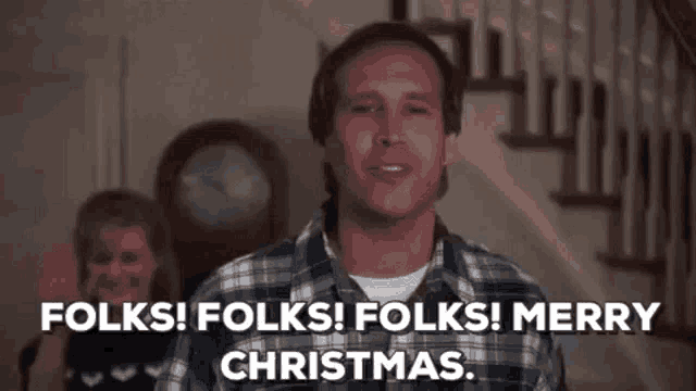 a man in a plaid shirt is saying `` folks ! folks ! merry christmas '' in front of stairs .