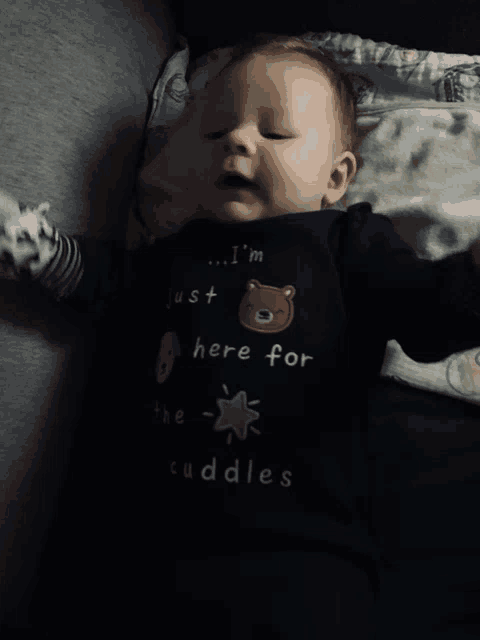 a baby wearing a shirt that says just here for the cuddles