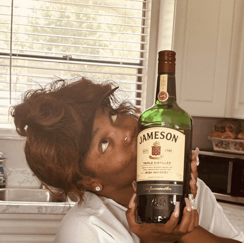 a woman is holding a bottle of jameson